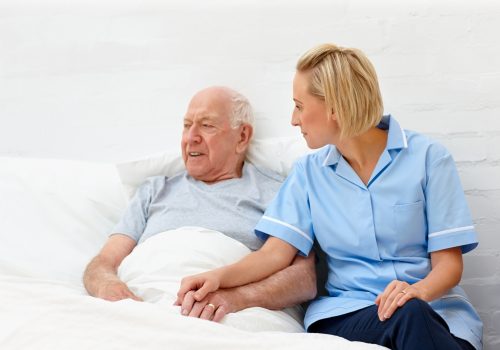 Caring healthcare worker consoling elderly patient in care home